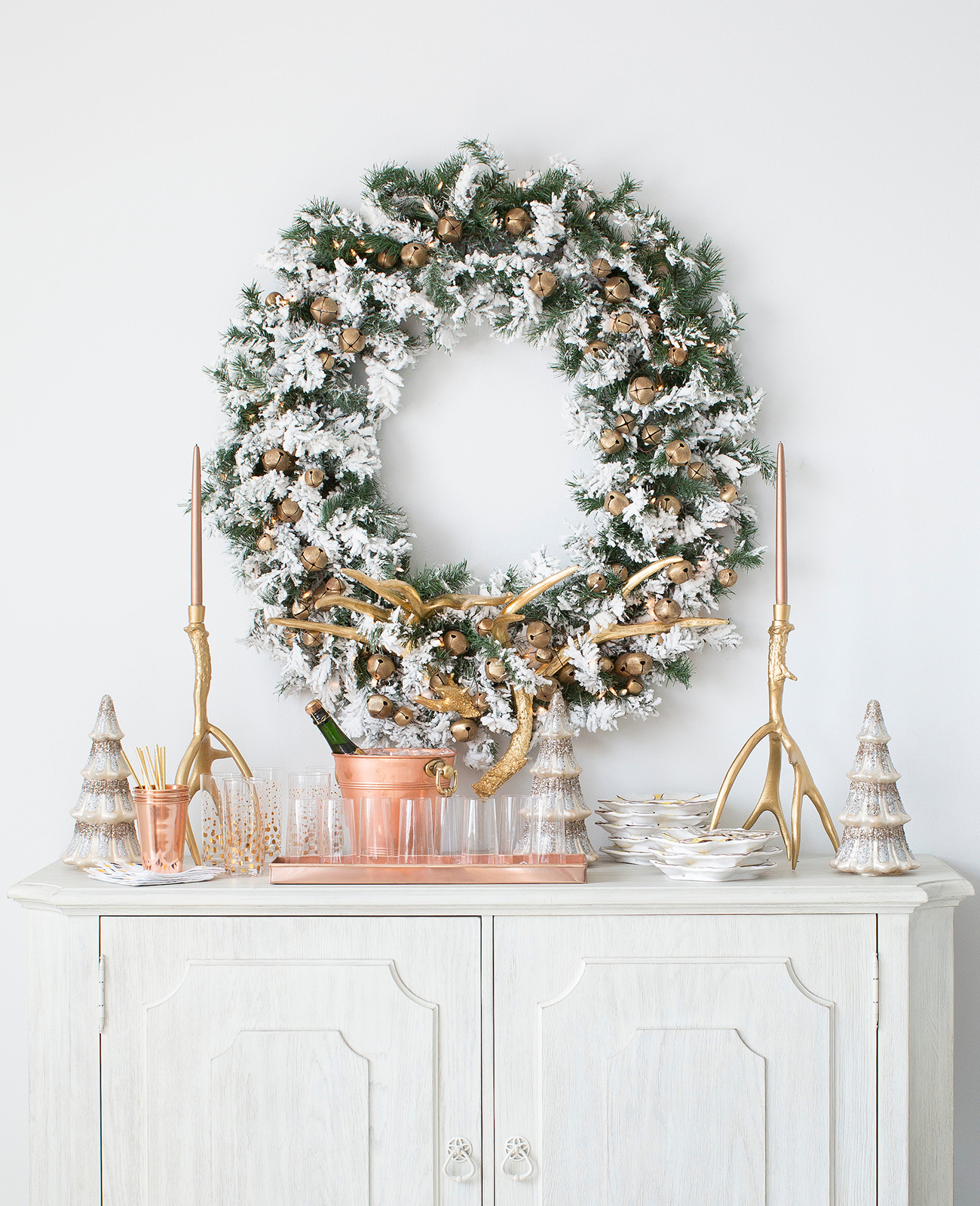 Holiday vignette of wreath over a credenza with cocktail party setup