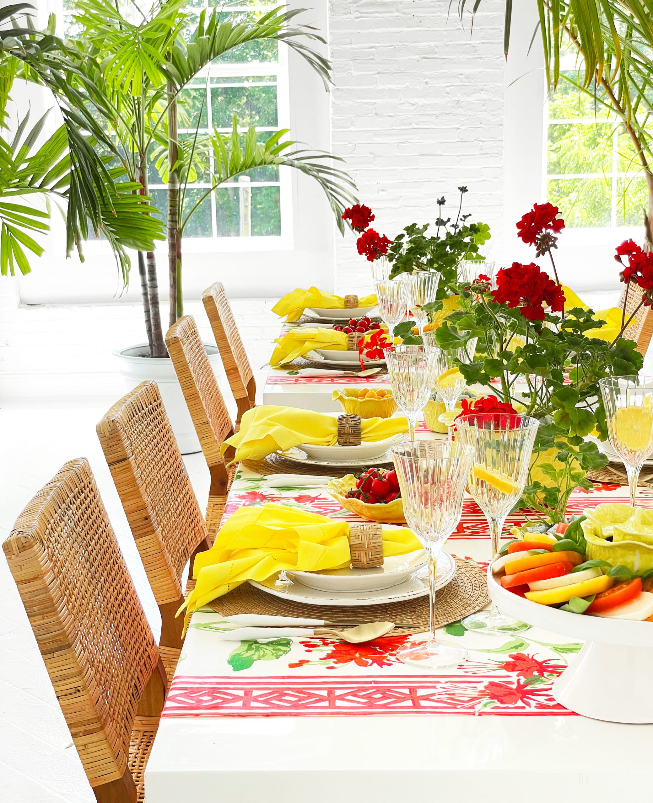 Table setting with yellow tableware and red geraniums inspired by Positano, Italy