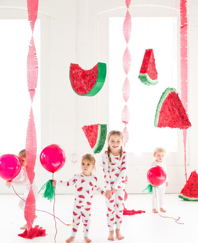 Young children in watermelon-printed pajamas with streamers